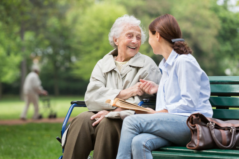 Une femme âgée discute avec une femme plus jeune sur un banc dans un parc