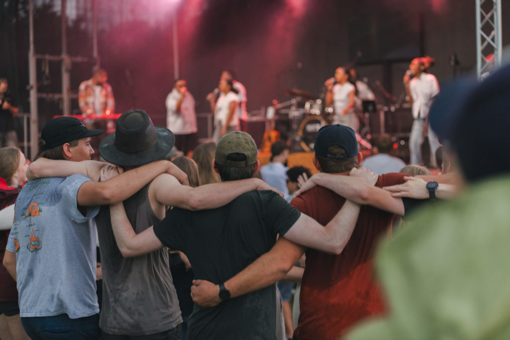 Des jeunes écoutent le concert de Mirella sous la pluie, bras dessus bras dessous