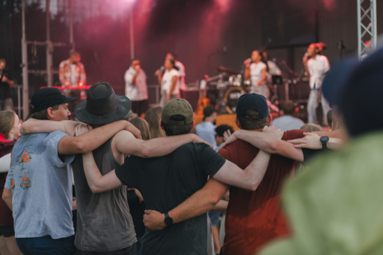Des jeunes écoutent le concert de Mirella sous la pluie, bras dessus bras dessous