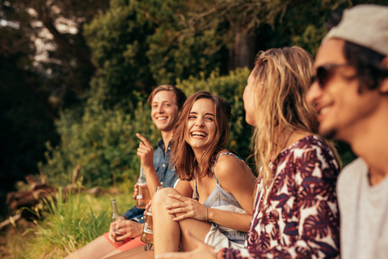 Un groupe de jeunes adultes s'esclaffe au soleil couchant