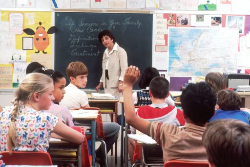 Un femme enseigne devant de jeunes élèves dans une salle de classe
