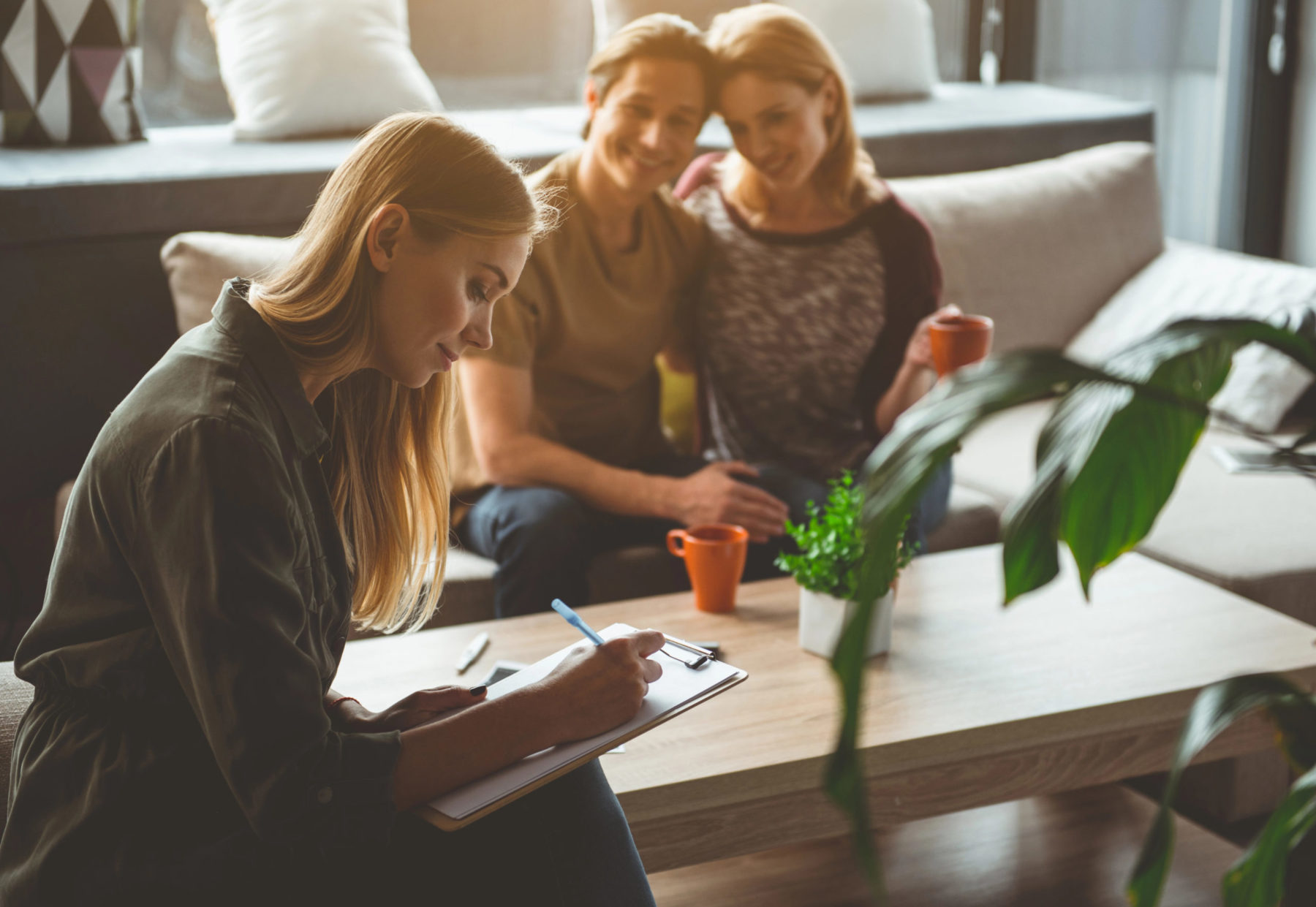 Un couple regarde tendrement une jeune femme qui signe des papiers en vue d'une gestation pour autrui
