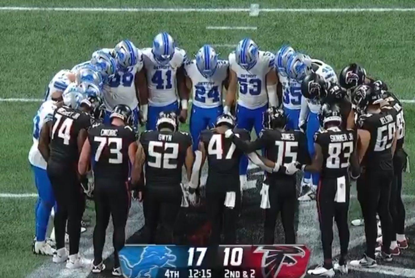 Des joueurs de football américain en cercle se tiennent la main et prient.