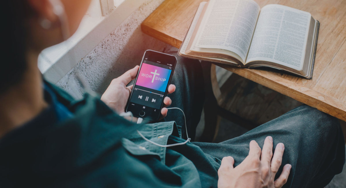 Bible ouverte sur papier et application numérique, illustrant la lecture digitale et papier en 2024 selon le rapport de l’Alliance biblique universelle.