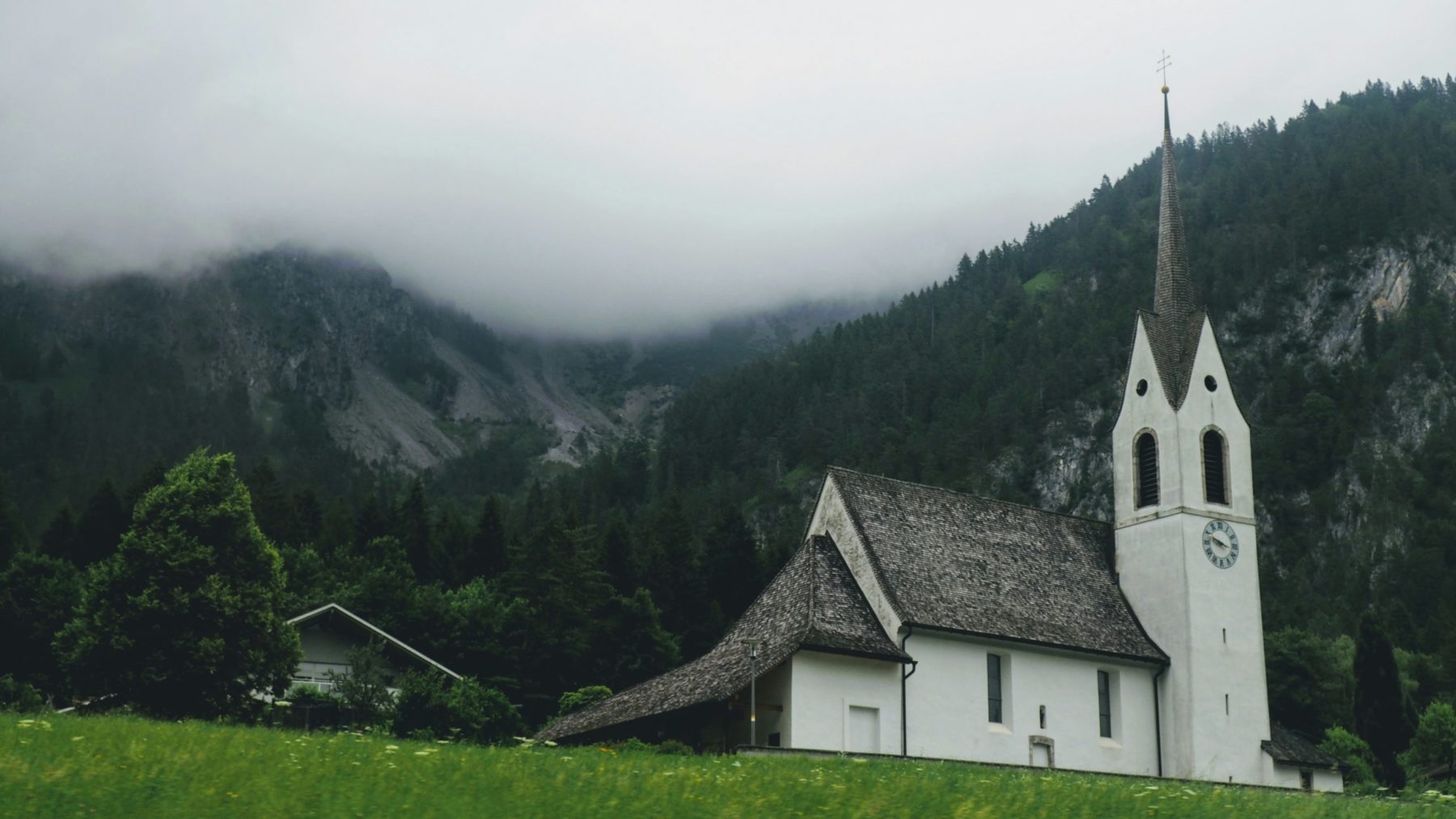 Une Eglise photographiée dans un paysage suisse un jour de brouillard
