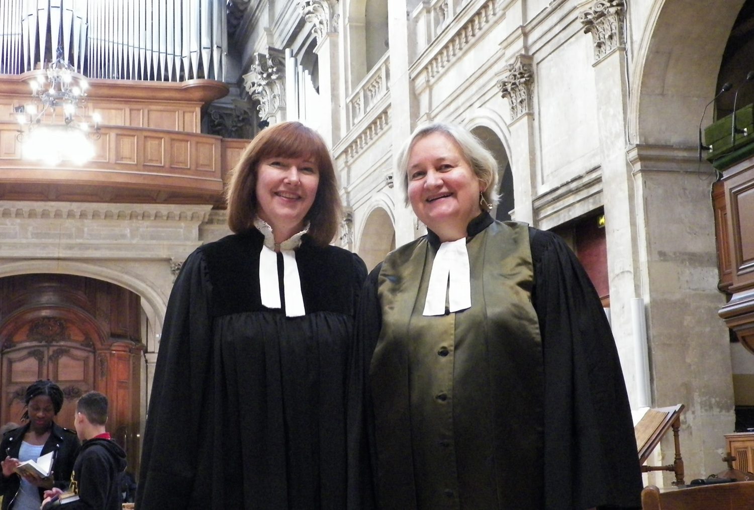 Les deux pasteures du temple protestant de l'Oratoire du Louvre dans l'Eglise avec en arrière-plan un orgue. Elles portent une robe pastorale noire et un col à rabat blanc