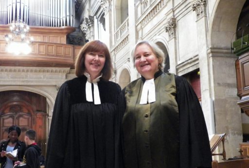 Les deux pasteures du temple protestant de l'Oratoire du Louvre dans l'Eglise avec en arrière-plan un orgue. Elles portent une robe pastorale noire et un col à rabat blanc