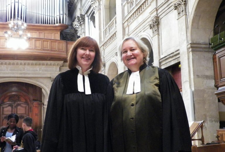 Les deux pasteures du temple protestant de l'Oratoire du Louvre dans l'Eglise avec en arrière-plan un orgue. Elles portent une robe pastorale noire et un col à rabat blanc