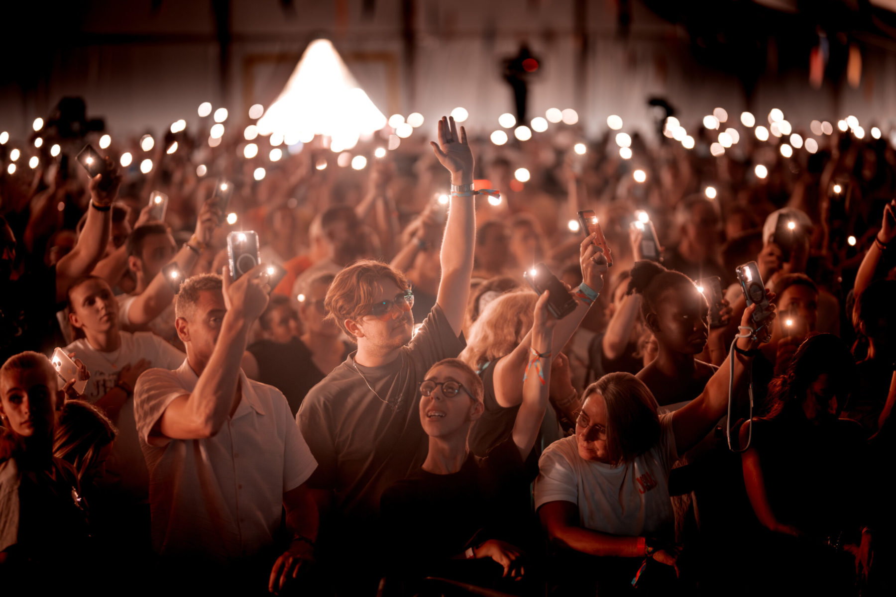 Photo de l'audience du Jesus Festival en soirée, avec des lumières orangées