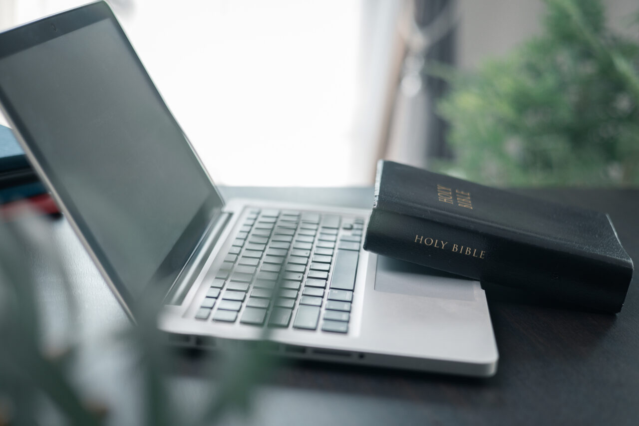 Une Bible posée sur un ordinateur, symbolisant la tension entre la Parole et ce que l'IA peut en faire.