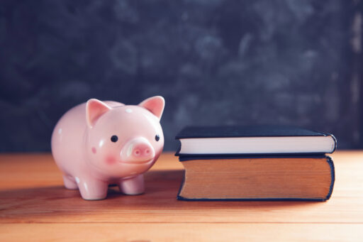 Un petit cochon-tirelire est placé près d'une pile de livres