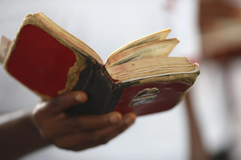Une main tient une bible en mauvais état.