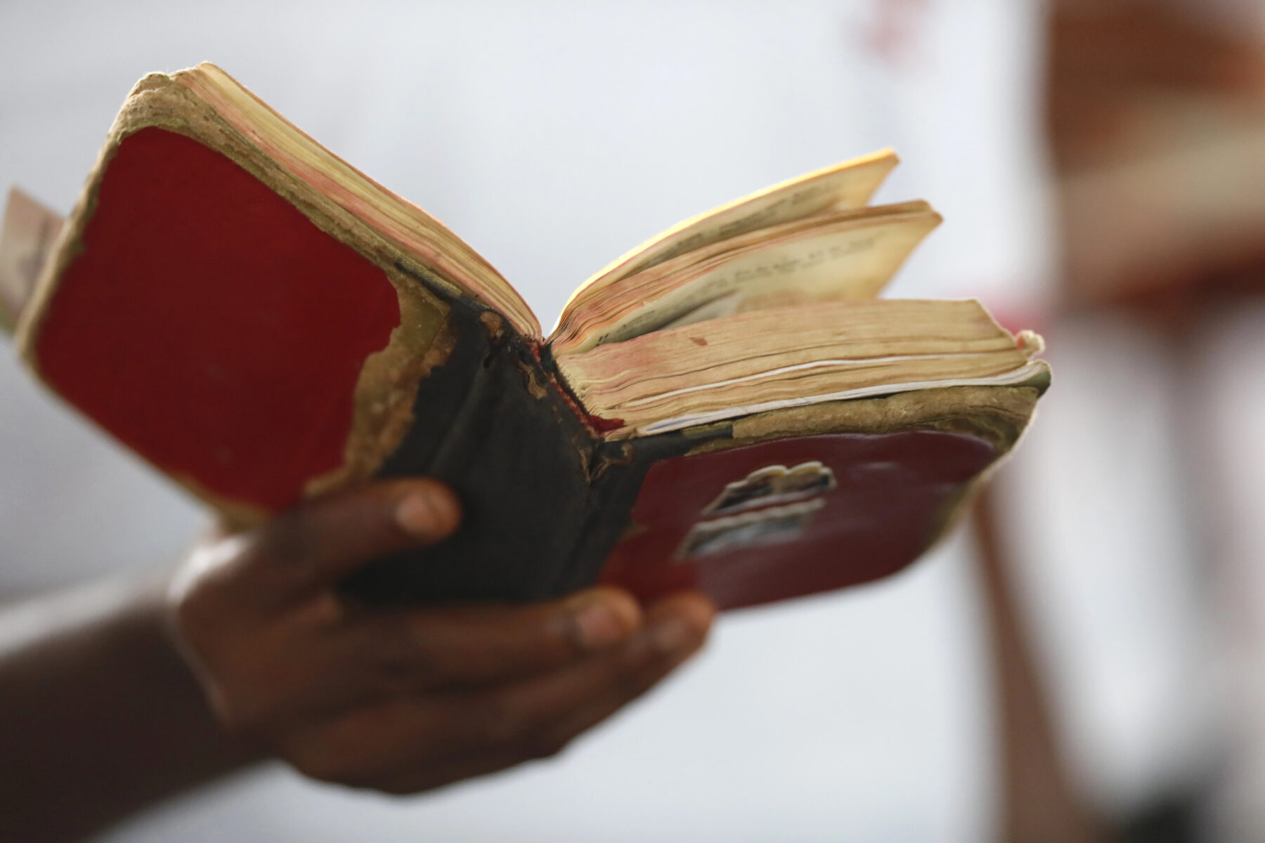 Une main tient une bible en mauvais état.