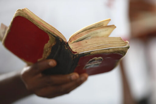 Une main tient une bible en mauvais état.