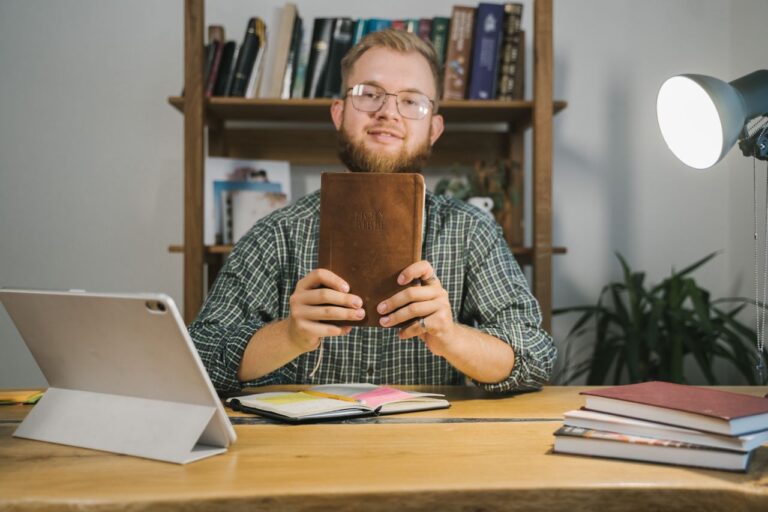 Un jeune homme dans son bureau tient une bible à la main